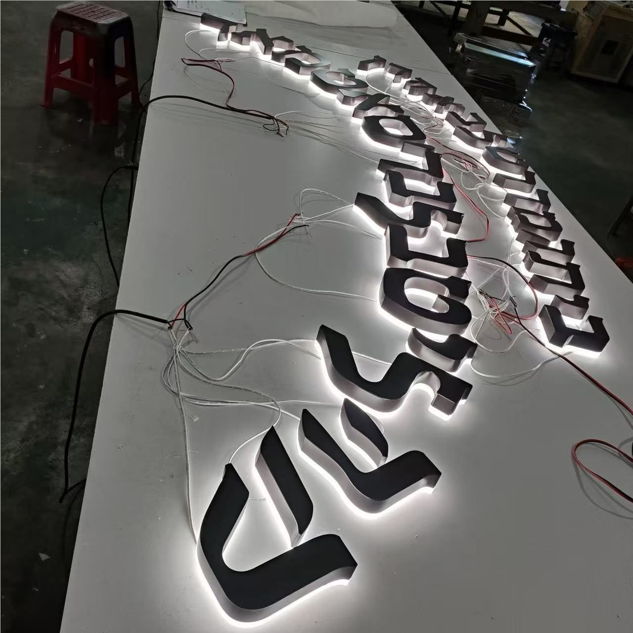 Custom halo-lit metal logo letters during workshop illumination testing
