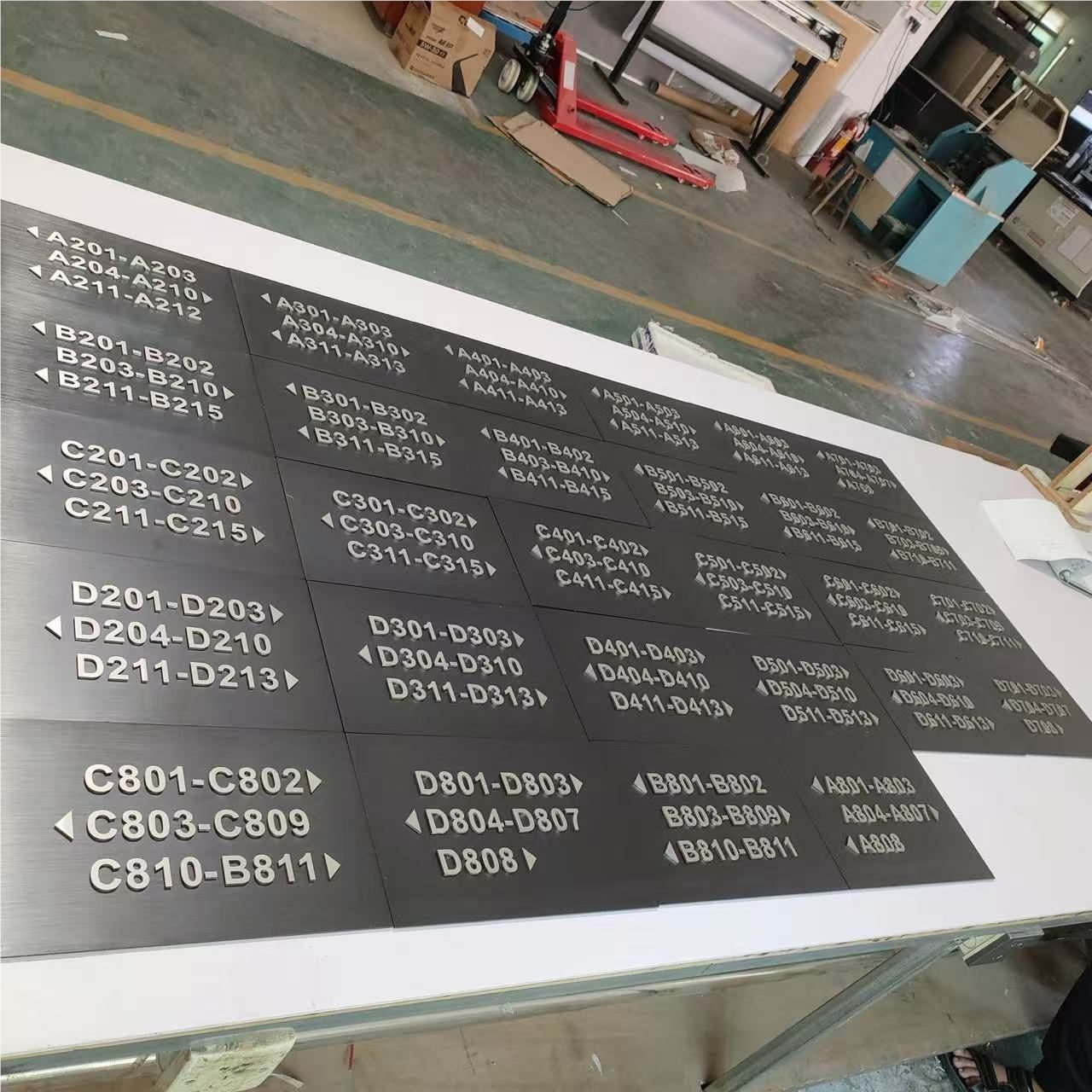 Dark metal hotel wayfinding panels with raised directional lettering